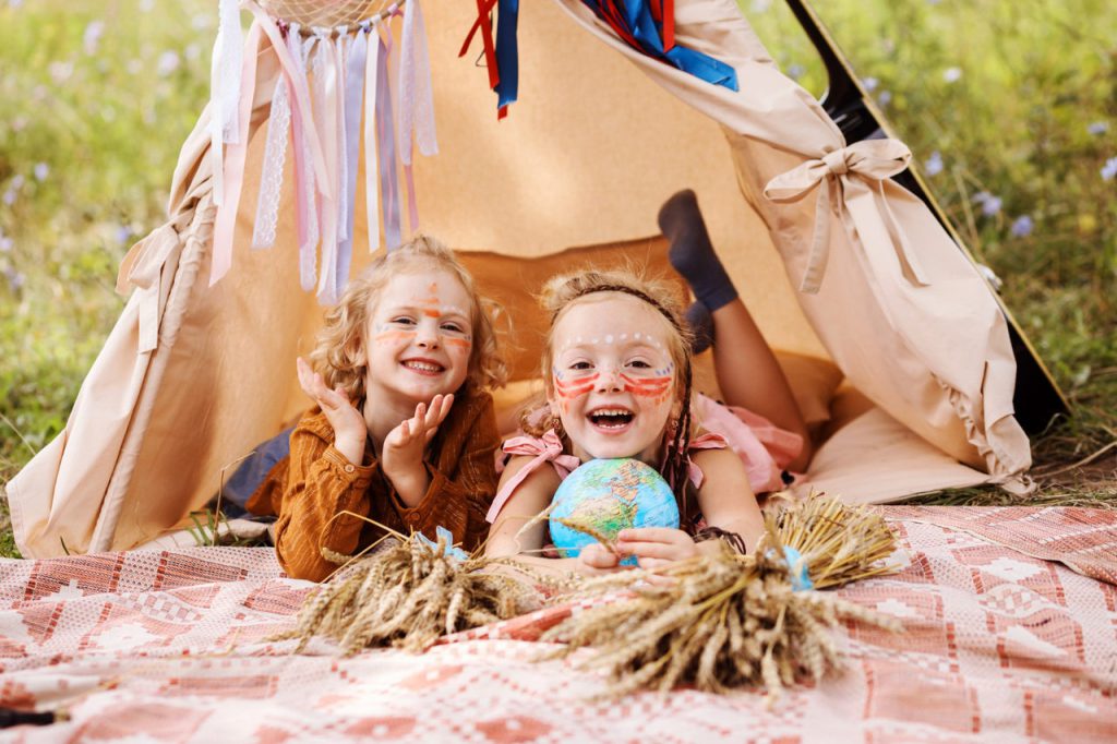 two-cheerful-little-girls-with-native-americans-make-up-on-their-faces-inside-wigwam-are-having-fun-outdoors-in-summer_Easy-Resize.com