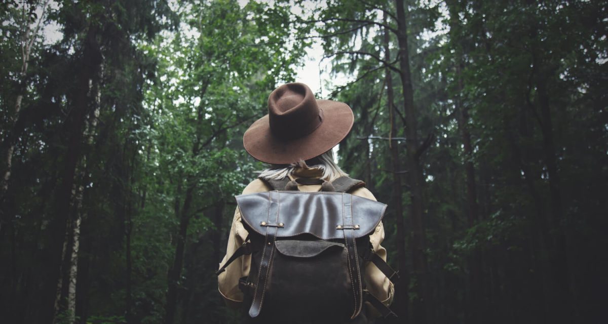 blonde-woman-in-hat-with-backpack-in-rainy-day-in-forest (1)